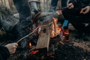 people cooking hotdogs over campfire